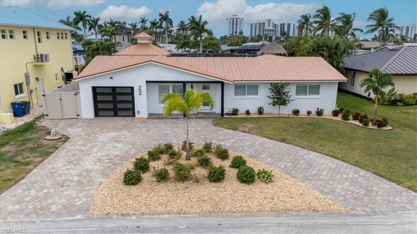 Ranch-style home featuring an attached garage, a metal roof, driveway, a front yard, and stucco siding
