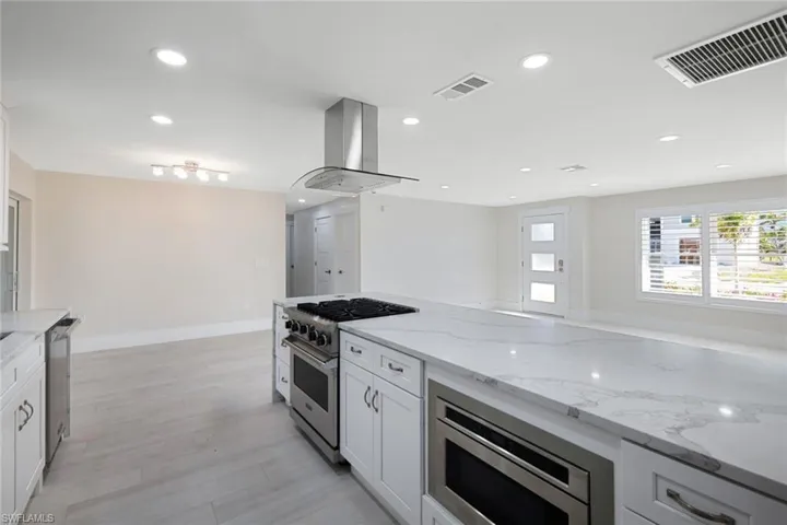 Kitchen featuring appliances with stainless steel finishes, range hood, visible vents, and recessed lighting