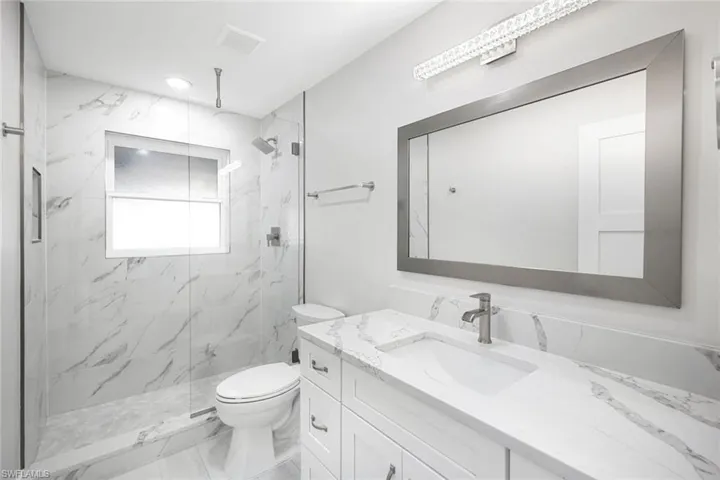 Full bath featuring vanity, visible vents, toilet, marble finish floor, and a marble finish shower