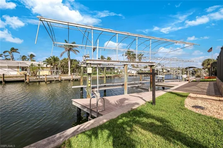 View of dock with a water view, a yard, and boat lift