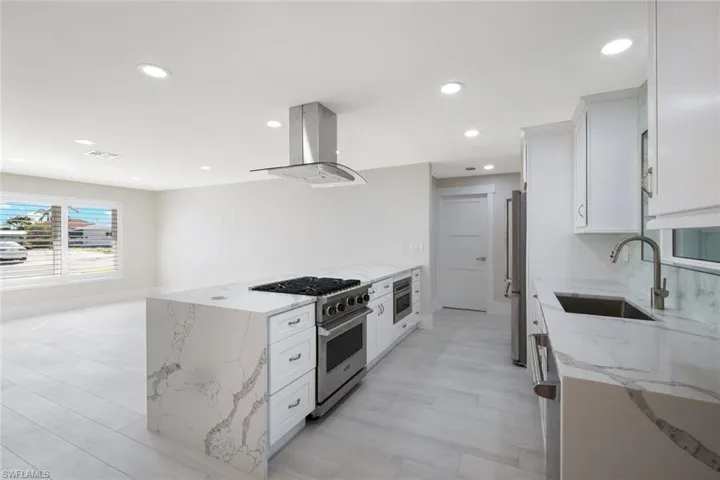 Kitchen with white cabinetry, visible vents, a sink, stainless steel appliances, and island range hood