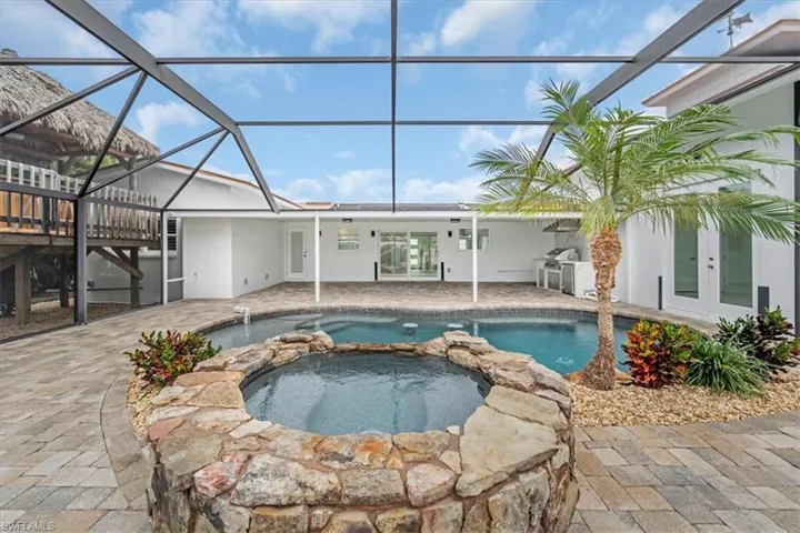 View of swimming pool featuring french doors, a patio, glass enclosure, and a pool with connected hot tub