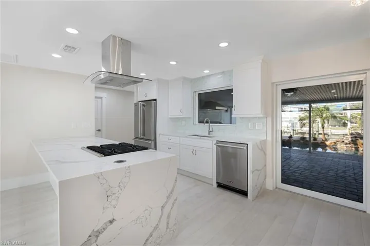 Kitchen featuring visible vents, white cabinets, a sink, stainless steel appliances, and island range hood
