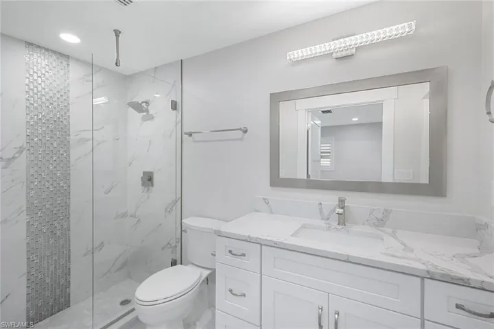 Full bathroom featuring toilet, a marble finish shower, vanity, and recessed lighting