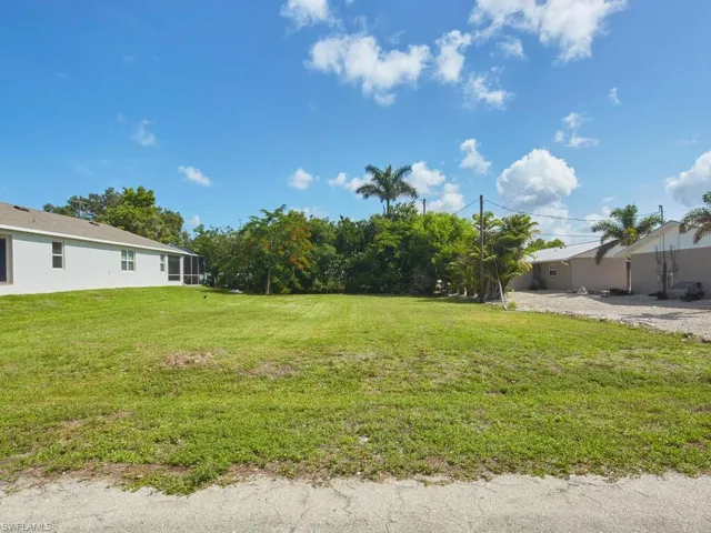 Street view of cleared lot in quiet neighborhood.