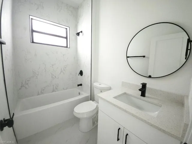 Full bathroom featuring tile flooring, tiled shower / bath combo, oversized vanity, and toilet