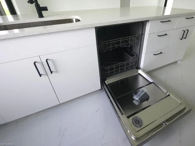Exterior details with light stone counters, white cabinets, and sink