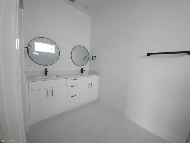 Bathroom with tile floors, vanity with extensive cabinet space, and double sink