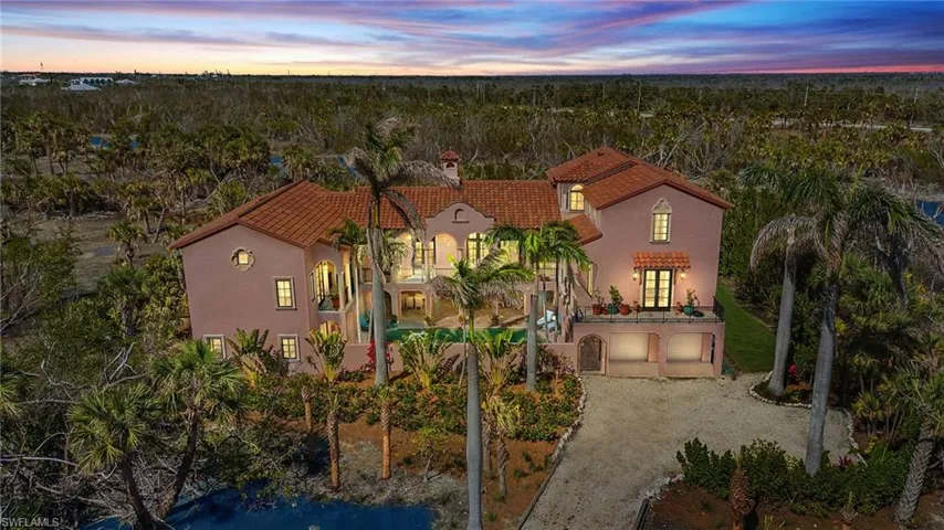 View of front of home featuring a tile roof, stucco siding, driveway, a patio area, and a chimney