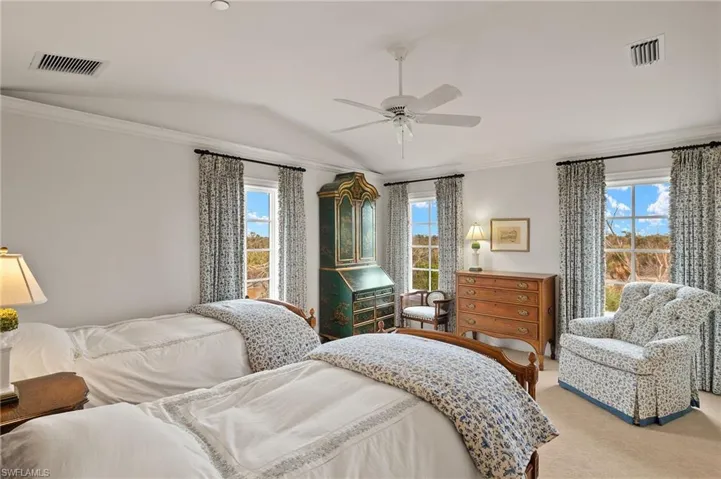 Bedroom with vaulted ceiling, multiple windows, ornamental molding, light carpet, and ceiling fan