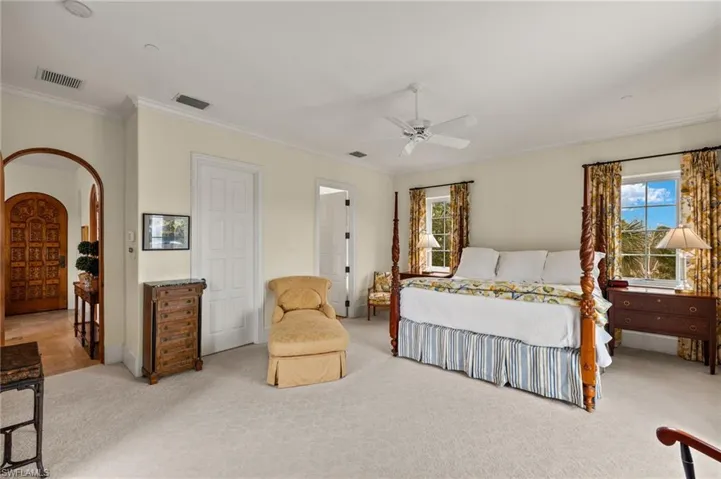 Bedroom with arched walkways, crown molding, carpet, and ceiling fan