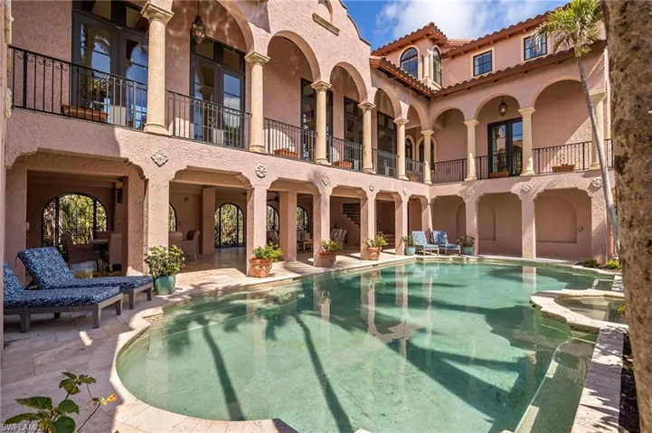 Rear view of house with stucco siding, a patio, a pool with connected hot tub, a tile roof, and a balcony