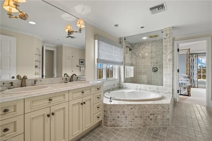 Ensuite bathroom with ornamental molding, double vanity, light tile patterned flooring, a garden tub, and a tile shower