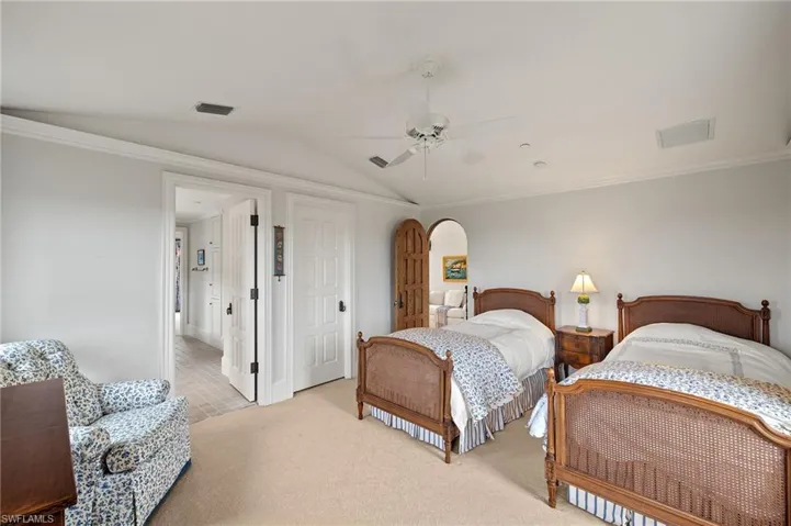 Carpeted bedroom featuring lofted ceiling, ornamental molding, arched walkways, and a ceiling fan