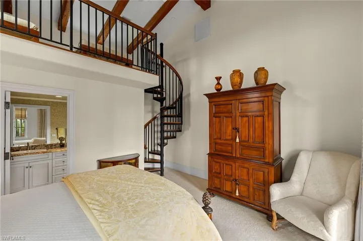 Bedroom featuring light colored carpet, high vaulted ceiling, ensuite bath, and beamed ceiling