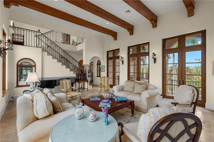 Living room with arched walkways, stairs, beam ceiling, a high ceiling, and french doors