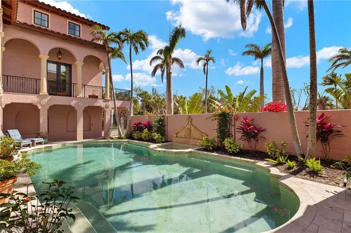 Swimming pool with a hot tub, a patio area, and a balcony