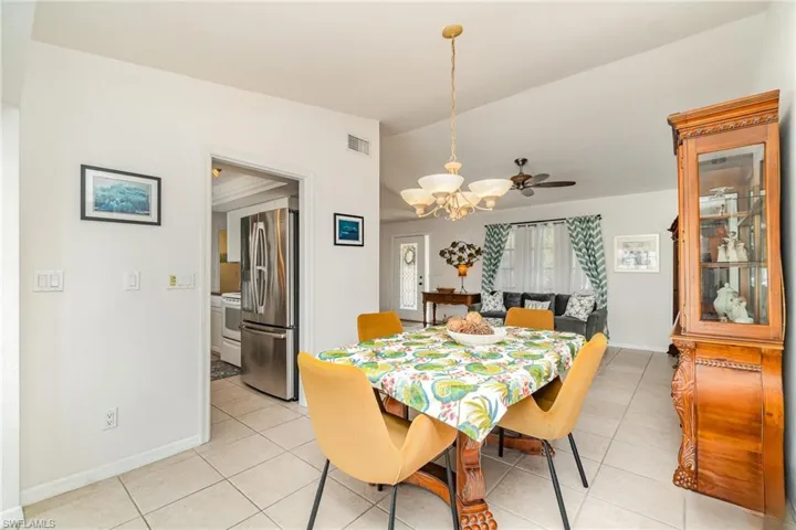 Living / Dining area with vaulted ceiling, light tile patterned flooring, ceiling fan, and a chandelier
