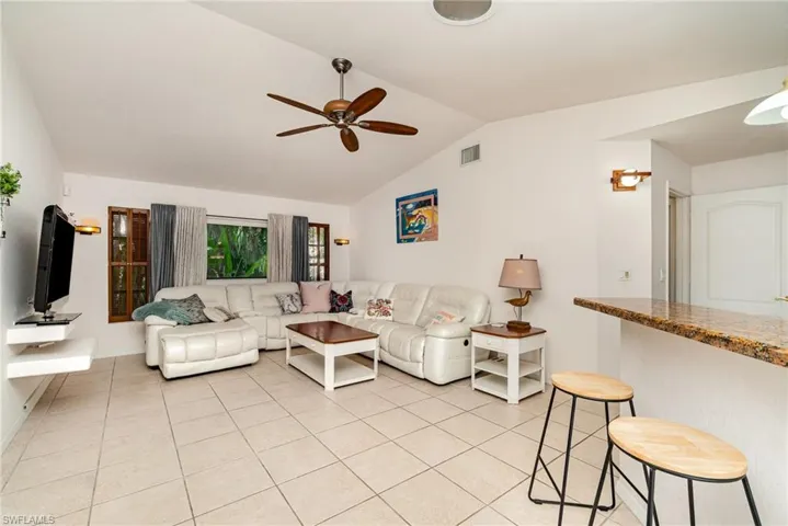 Large family room looking into Kitchen and Den area, displaying 2 seating breakfast bar.  Light tile flooring through out