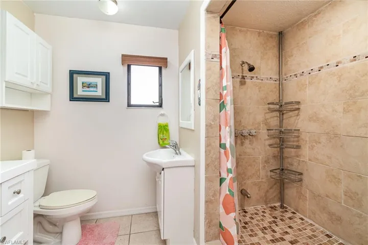 Guest bathroom featuring 2 separate sinks and white overhead storage cabinets and a window