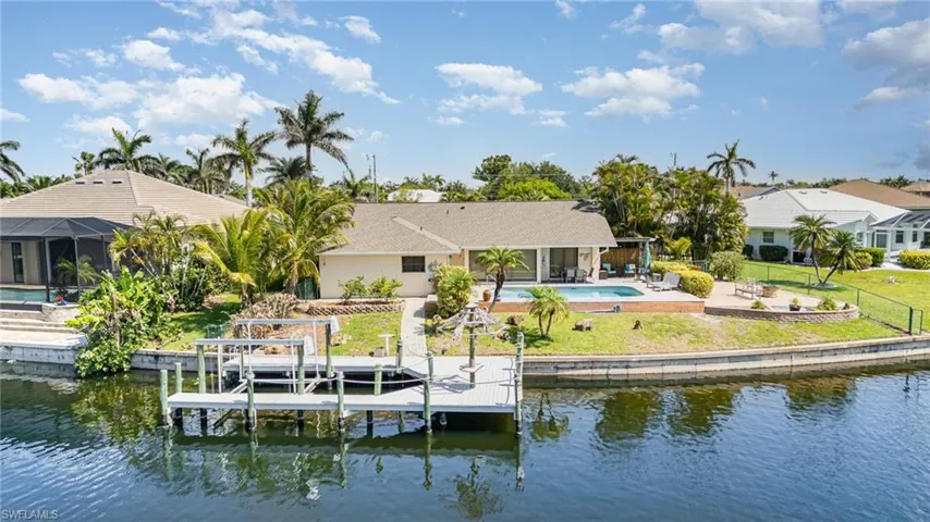 Aerial Rear view of house with a water view, boat lift, a patio area, and an outdoor pool, 135' of seawall