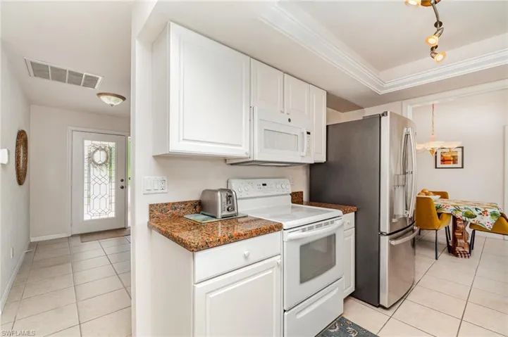 Kitchen with stainless steel dishwasher, a double sink, light tile floors, rail lighting, and a breakfast bar for 2.  Water view visiable while doing the dishes!!!