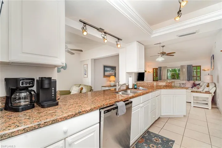 Large family room off kitchen breakfast bar with light tile patterned flooring, sconce lighting and ceiling fan
