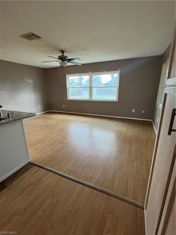 Unfurnished living room with sink, hardwood / wood-style floors, and ceiling fan
