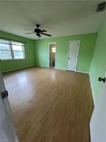 Empty room with ceiling fan and light hardwood / wood-style floors