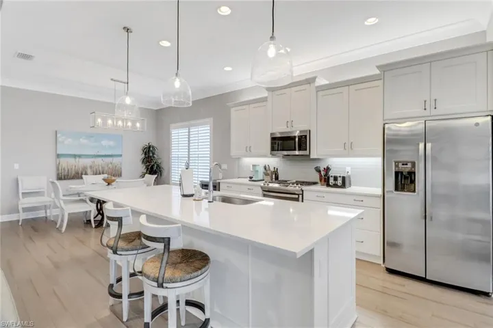 Kitchen with stainless steel appliances, sink, tasteful backsplash, pendant lighting, and a kitchen island with sink