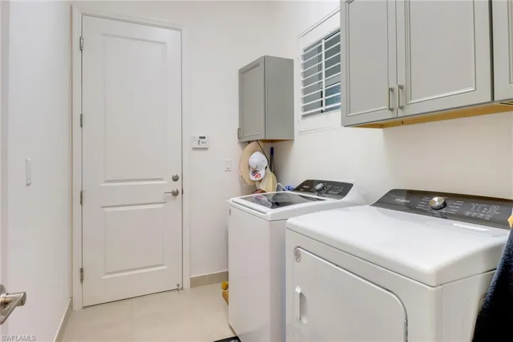 Laundry  featuring cabinets, light tile patterned flooring, and washing machine and clothes dryer