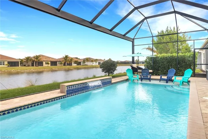 View of pool with a lanai, pool water feature, a patio area, and a water view