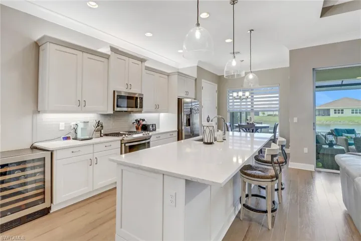 Kitchen featuring hanging light fixtures, a kitchen island with sink, appliances with stainless steel finishes, and sink