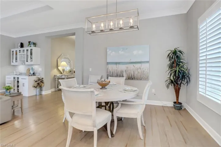 Dining area featuring wine cooler, an inviting chandelier, crown molding, and light hardwood / wood-style flooring