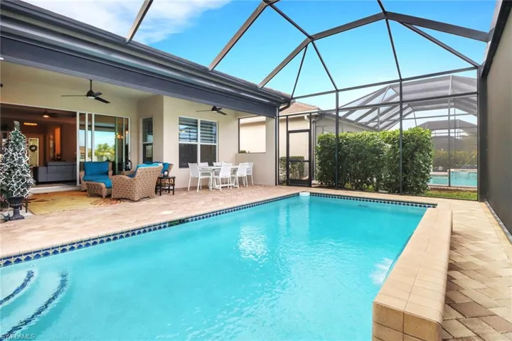 View of swimming pool featuring ceiling fan, outdoor lounge area, a patio, and a lanai