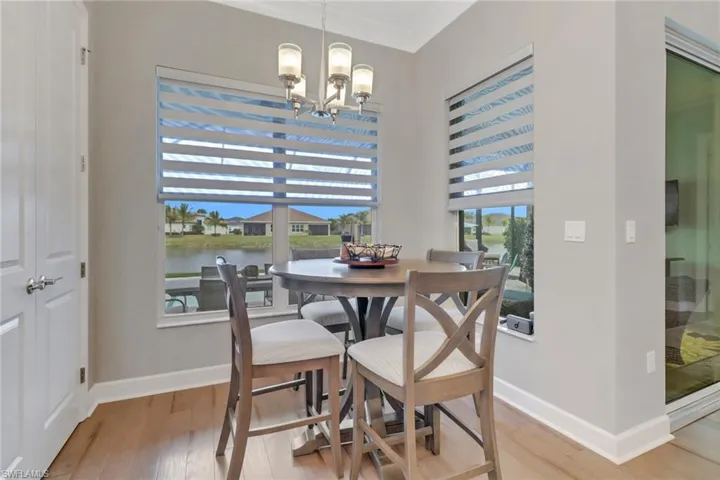 Dining space featuring wood-type flooring, a chandelier, ornamental molding, and a water view