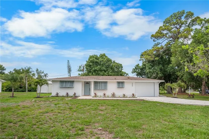 Ranch-style residence featuring a white stucco exterior, an attached single-car garage, and a light blue entry door