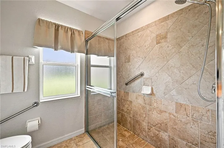 Spa-inspired guest bathroom featuring a walk-in shower with glass enclosure, detachable showerhead, and tile surround