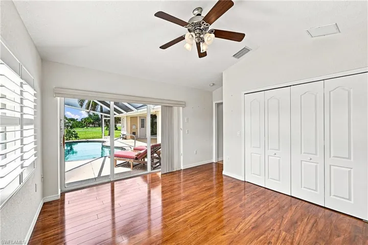 Guest bedroom featuring double closets, wood style flooring and sliding doors to the pool area