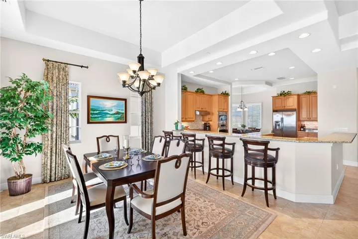 Dining area with a chandelier, a raised ceiling, recessed lighting, and light tile patterned flooring