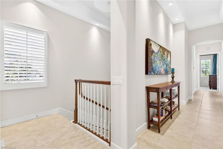 Hall with arched walkways, light tile patterned floors, and recessed lighting