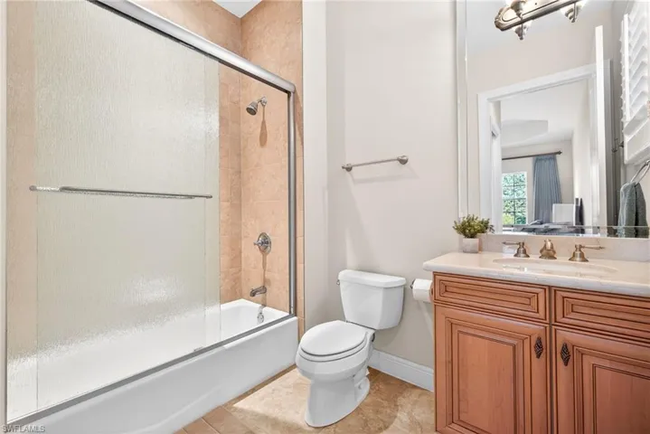 Bathroom featuring combined bath / shower with glass door, vanity, and light tile patterned flooring