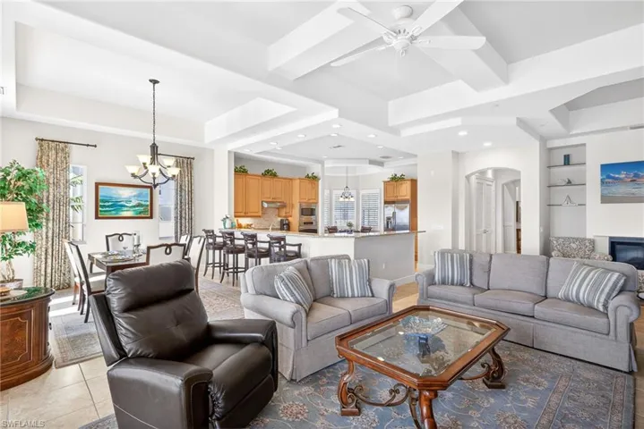 Living room with a chandelier, a raised ceiling, built in shelves, light tile patterned floors, and recessed lighting