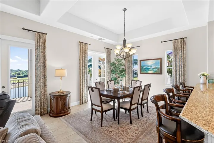 Dining area with french doors, a chandelier, a tray ceiling, and light tile patterned flooring
