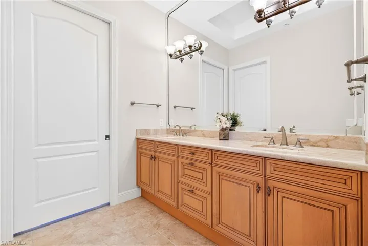Bathroom featuring double vanity, light tile patterned floors, and a tray ceiling