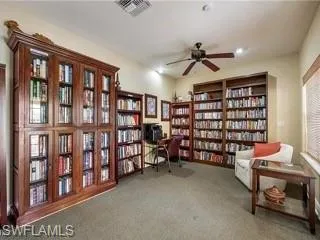 Living area with bookshelves, ceiling fan, and carpet floors