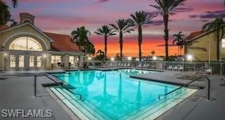 Pool at dusk featuring a patio and a community pool