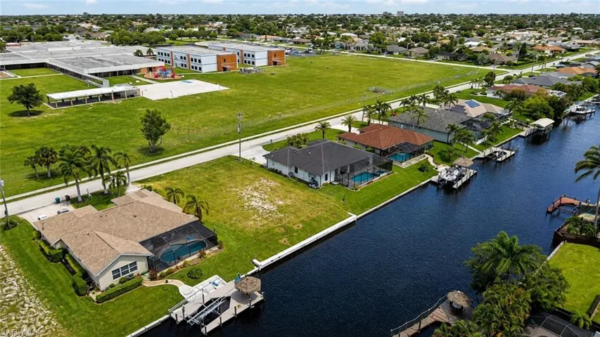Waterfront property featuring expansive manicured grounds with mature landscaping, direct canal access with boat dock, and multiple residential structures including a primary residence and guest cottage