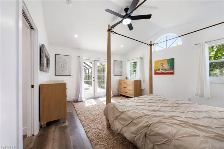 Vaulted ceiling, wood-finish flooring, ceiling fan, French doors, and arched transom window