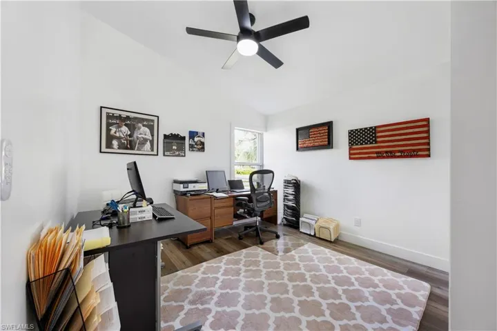 Vaulted ceiling, wood-finish flooring, ceiling fan, and window